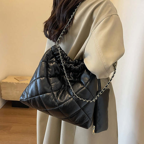 Woman carrying black PU leather bucket bag with chain strap, European and American retro style, perfect for leisure travel.